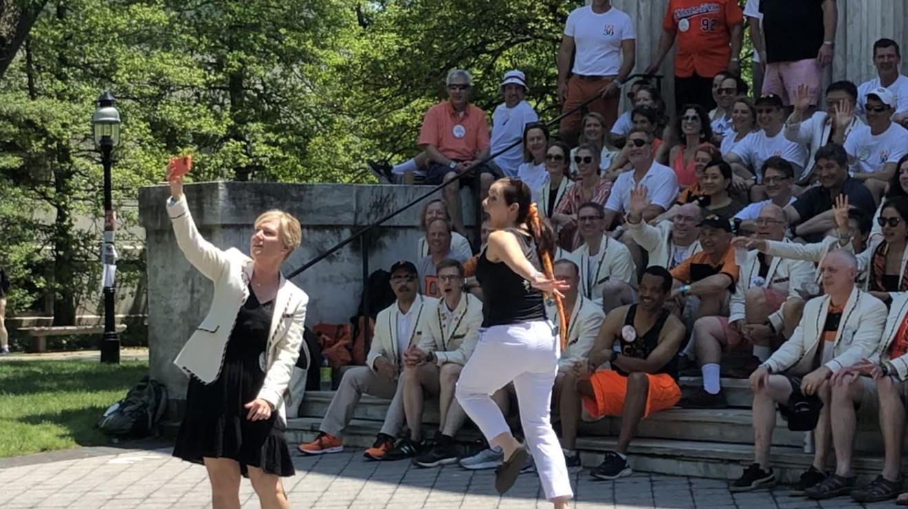 One alumna snaps a selfie while another jumps in the background.