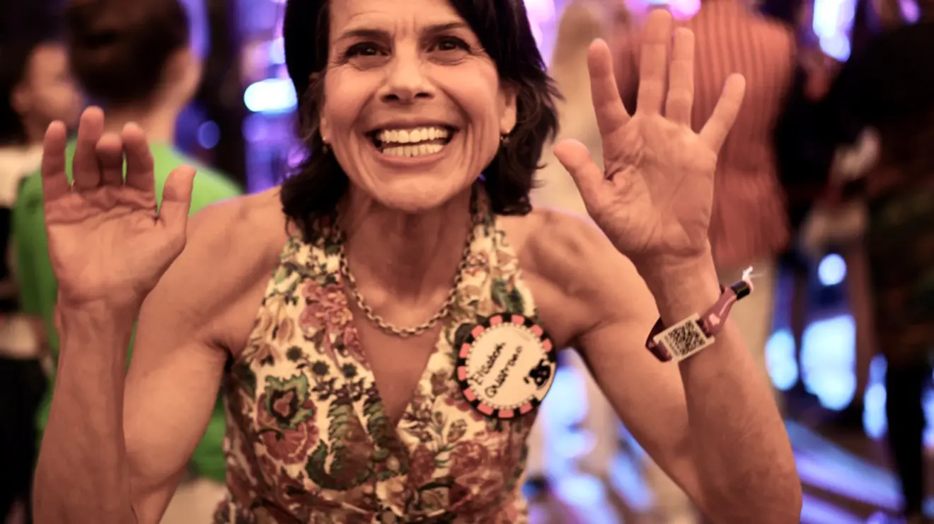 A woman smiles for the camera and holds up her hands.