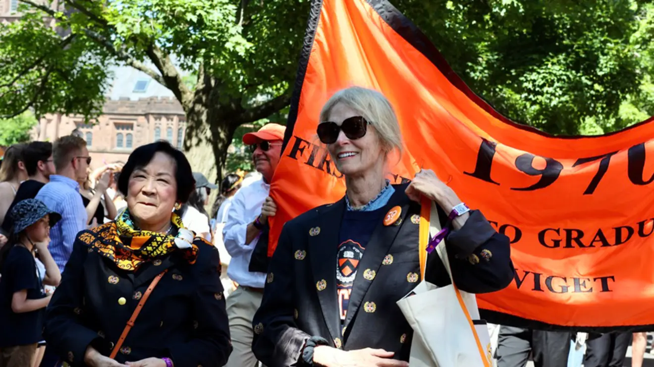 Two women in front of a 1970 banner.