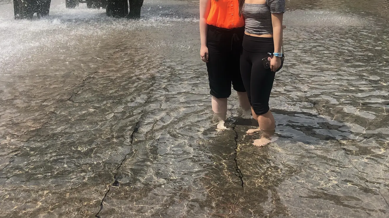 Two women stand in the fountain by SPIA.