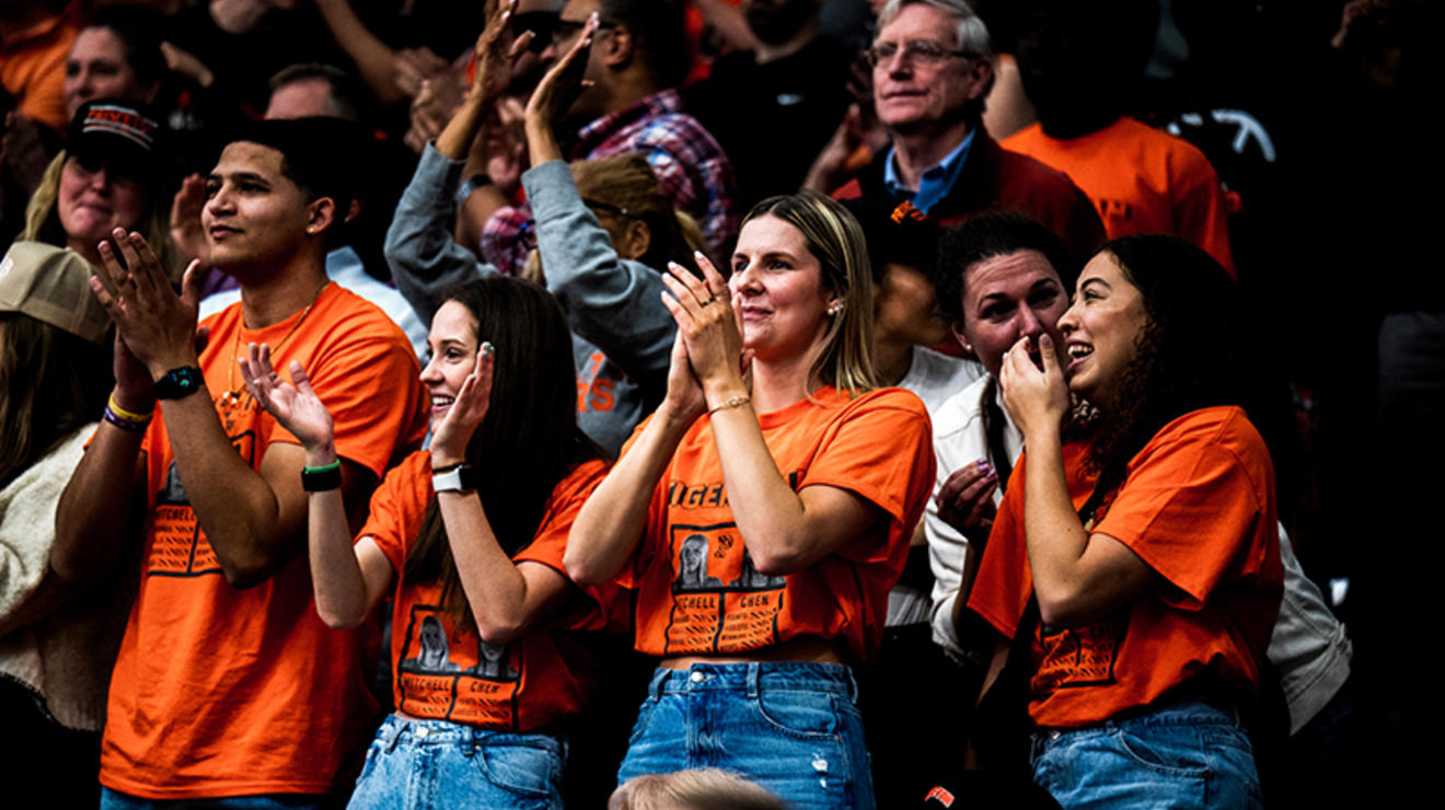 Orange T-shirt-clad fans cheer in the bleachers