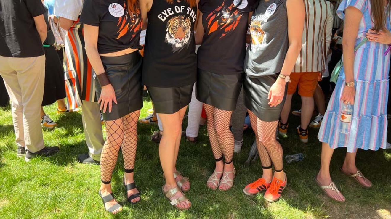 Four women wearing spiky 80’s wigs, fishnet tights, aviator sunglasses, and "Eye of the Tiger" T-shirts.