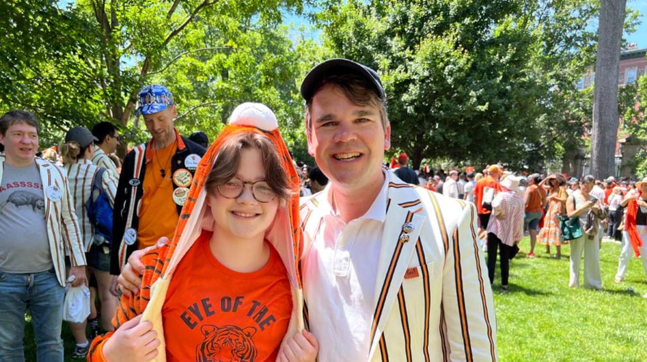 A father and son; the son is wearing a tiger costume and a T-shirt that says "Eye of the Tiger."