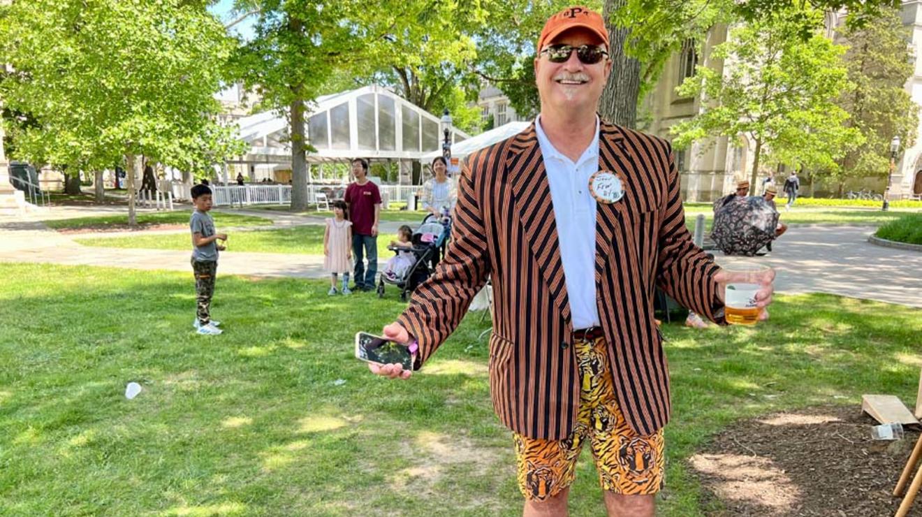 A man wearing tiger shorts and orange sneakers with his reunions jacket.