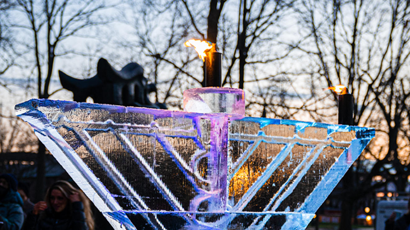 A view of the ice menorah, lit up in blue and purple.