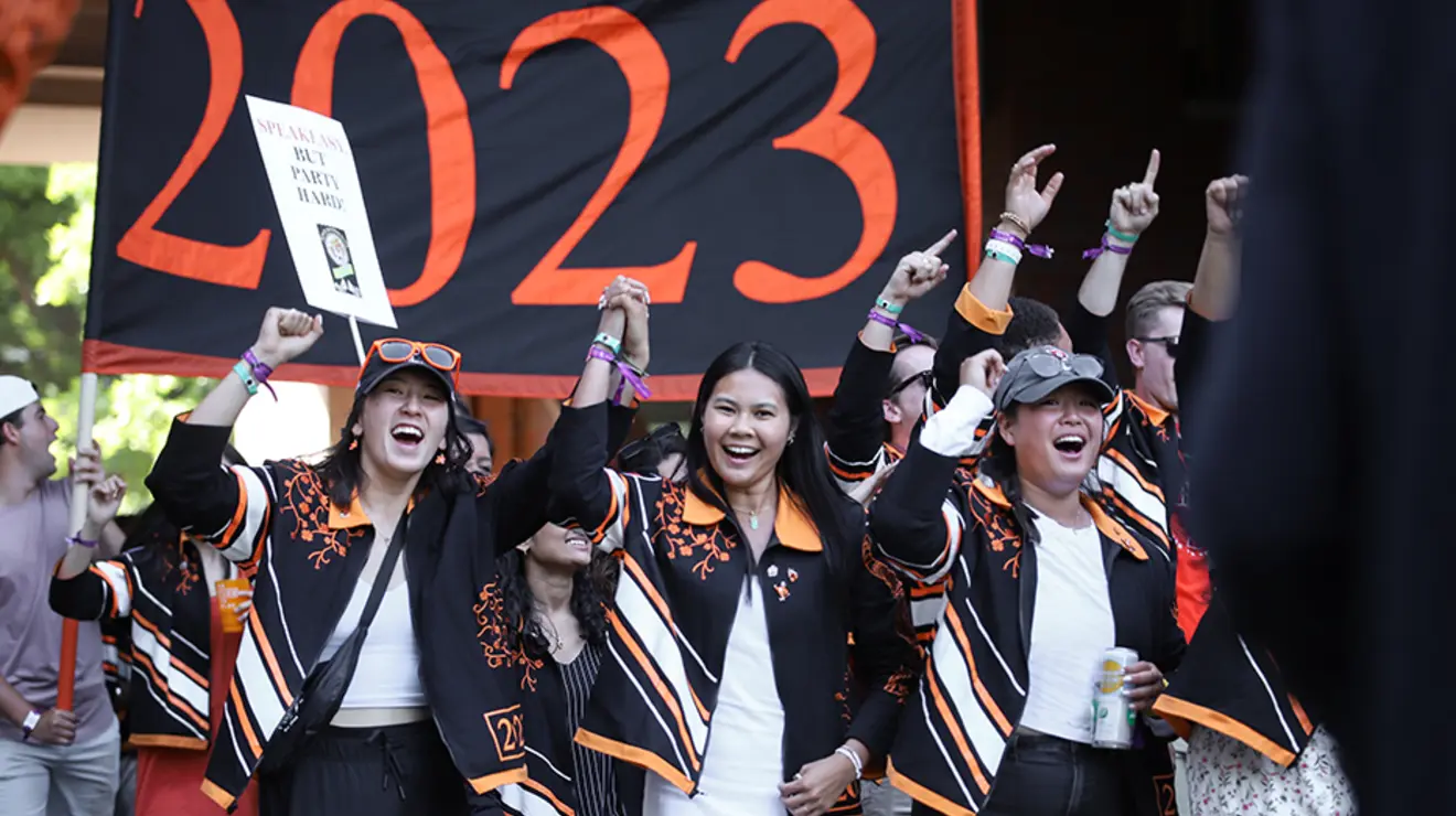 Women cheer in front of the "2023" banner.