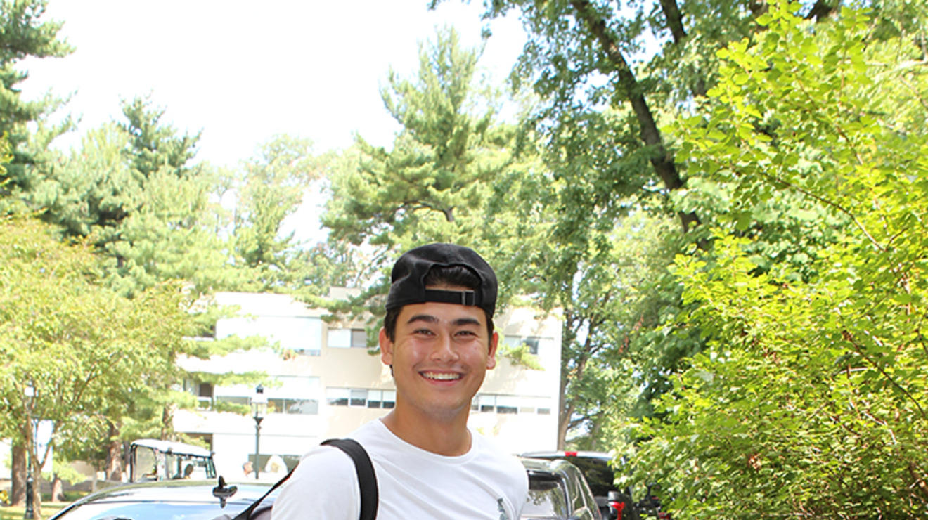 Jayden Sison ’26 holds an electric fan in one hand with a duffle bag over his shoulder.