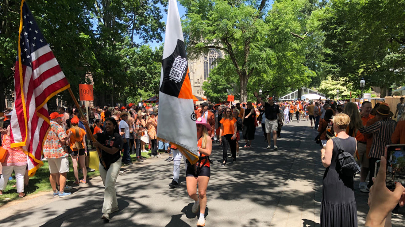 Alumni holding flags march in the P-rade.