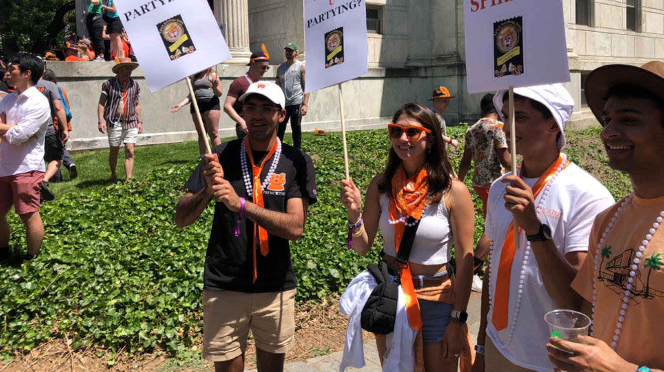 Alumni hold signs reading, "Orange U Partying?" and "Banned: Dour Spirits!"