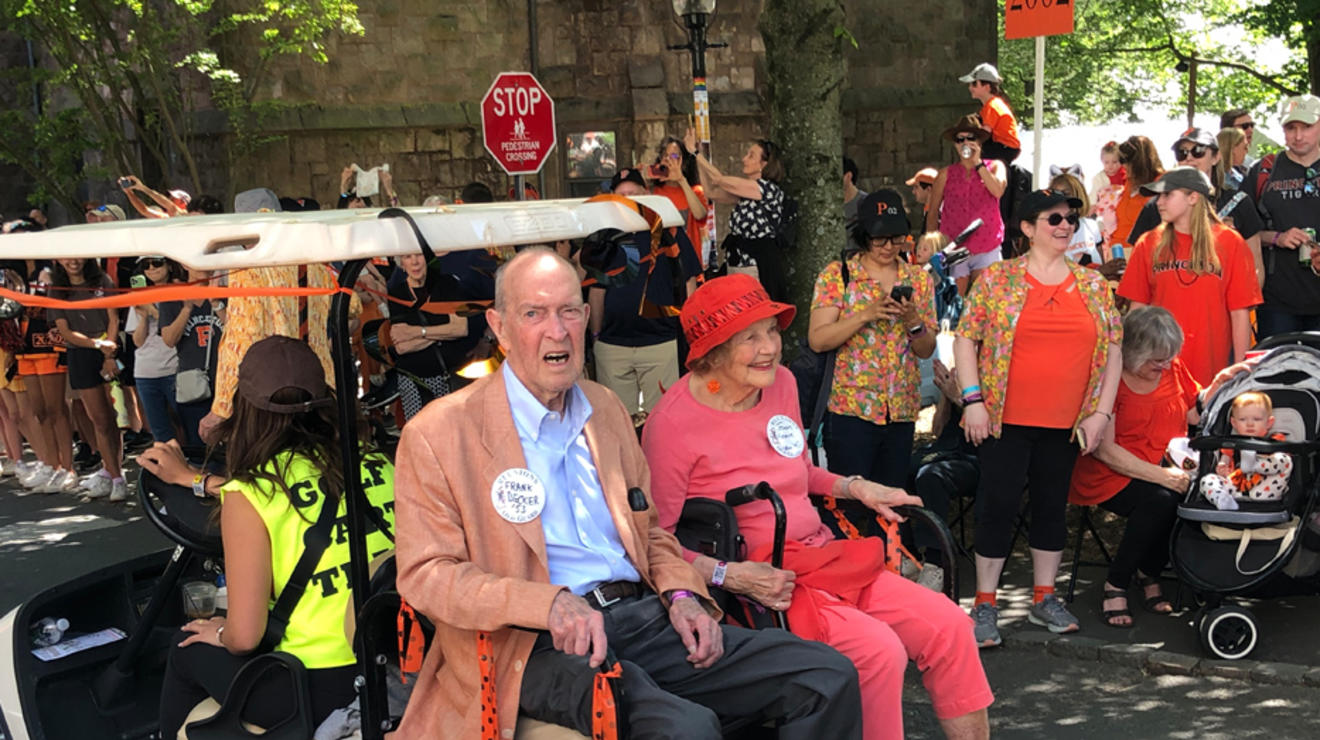 Two people sit on the back of a golf cart in the P-rade.