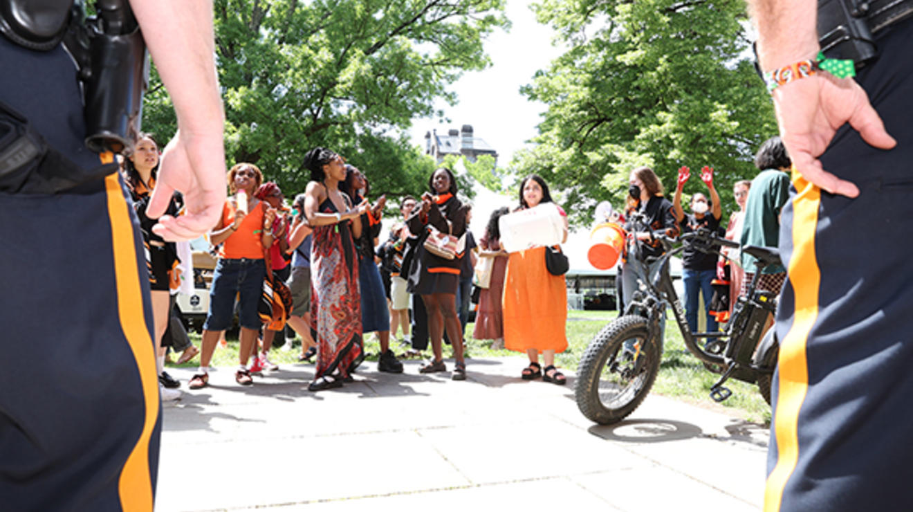 The view between two police officers shows several alumni and a bicycle.