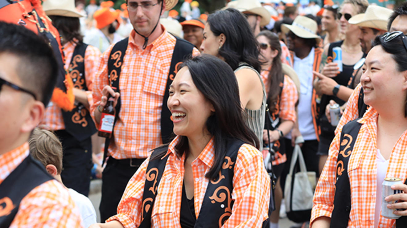 Alumni wearing orange plaid shirts march in the P-rade.