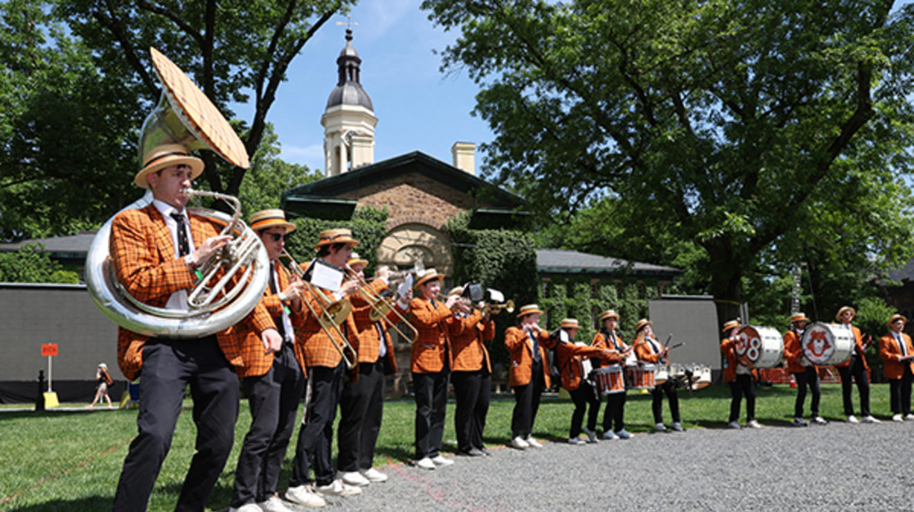 The marching band stands around the edge of the gravel circle on Cannon Green.