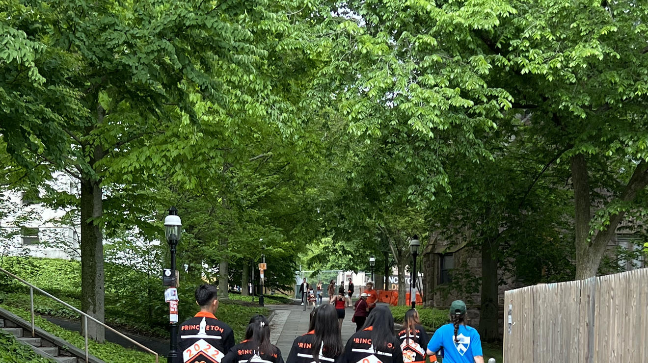 Four students in the Class of 2022 walk down a stone path with their class jackets on.