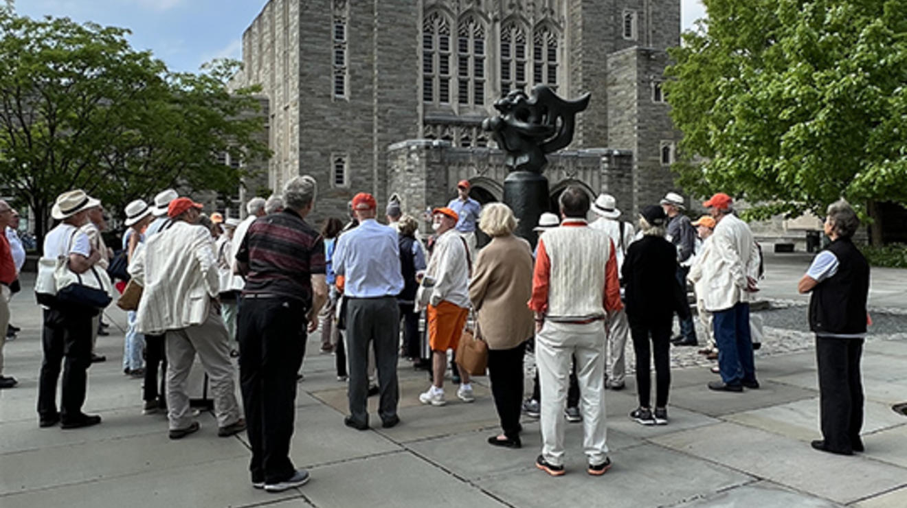 Alumni take a tour of campus with Firestone Library in the background.