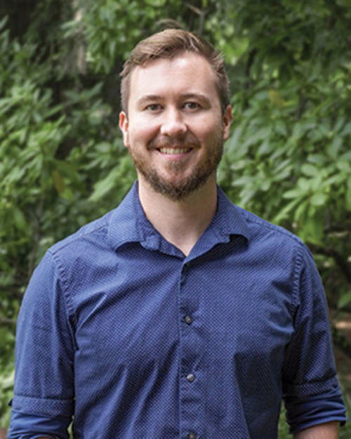 photo of Christopher Griffin standing in front of a lush forest background