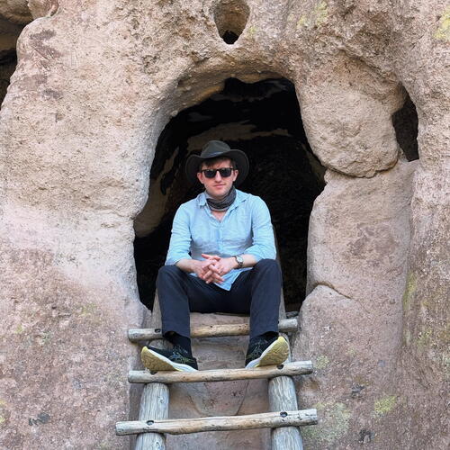 Harrison_BandelierNationalMonument-Taos_Tiger-Travels.jpg Writer Harrison Blackman ’17 is sitting within the stone structure of a Ancestral Pueblo ruins at Bandelier National Monument. He wears a black hat, black sunglasses, and a blue button up shirt.