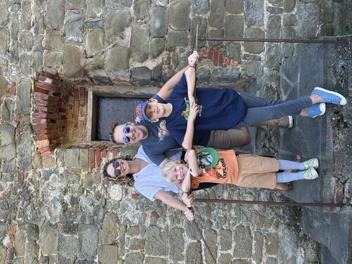 Author Kate Gammon ’03 stands with her husband and kids in front of a stone building.