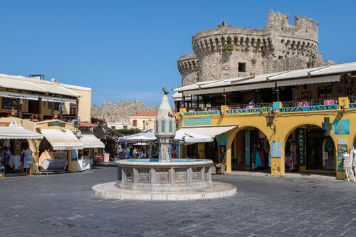 Tiger-Travels_Rhodes-Greece-Old-Town.jpeg A fountain sits in the middle of several brick stores and archways