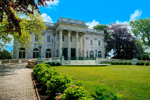 Tiger-Travels_Newport-Rhode-Island_Jennifer-Roosth_Marble-House.jpeg View of the front of Marble House and the green lawn and surrounding trees