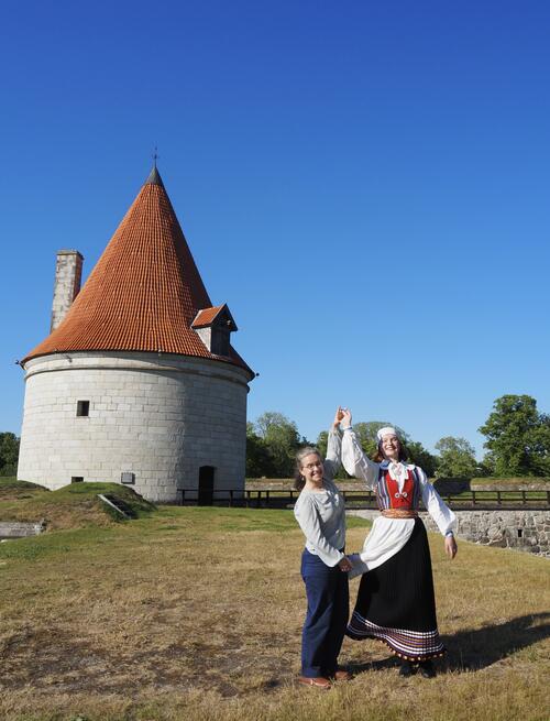 mother and daughter stand to the right of Kuressaare Castle, a white building with a red roof.