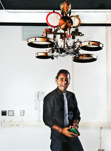 Ajay Kapur ’02, a professor at the California Institute of the Arts, develops robotic instruments. He stands beneath MahaDeviBot, which strikes 12 percussion instruments from India. The bouncing head can relay tempo to the human performer.