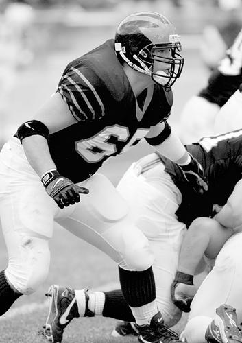 Black and white photo of Tucker executing a tackle on Princeton’s offensive line