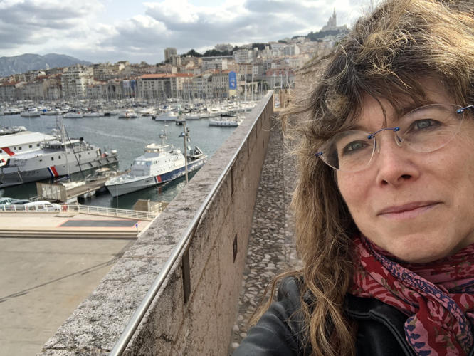 This is a selfie photo of Vedel in front of a harbor full of boats.