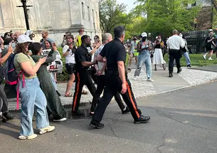 Public Safety police officers walk a man in handcuffs the night in April when student protestors staged a sit-in at Clio.