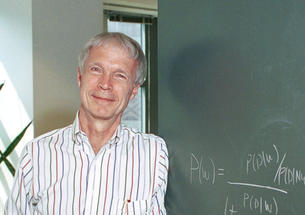 John Hopfield in front of a chalkboard