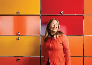 Kim Scott stands against a wall of yellow, orange, and red cabinets.