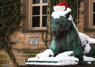 One of Princeton’s bronze tiger statues in the snow wearing a Santa hat.