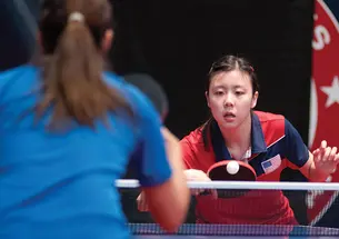 Two women play table tennis.