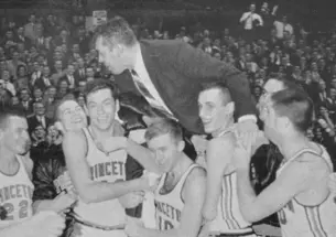 Group of basketball players lift their coach and carry him off the court