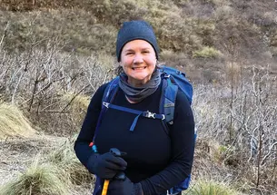 A woman smiles outdoors on a hike.