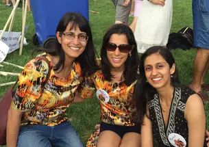 Three women sit on the grass.