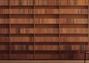 Long rows of old brown books with ladder reaching high up into the stacks