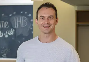 Headshot of a man with a chalkboard in the background.