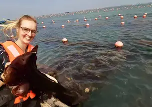 Helen Park sits in a boat holding a piece of kelp.