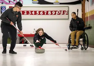 Three curling club members practice on the ice