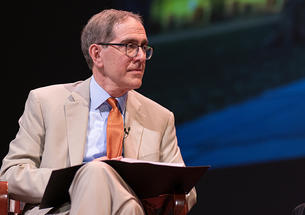 Princeton President Christopher Eisgruber ’83 holds an open binder on a stage.