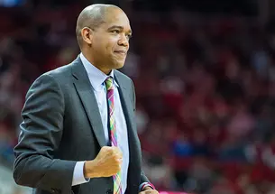 Sydney Johnson ’97 looks like something's going well as he curls one hand into a fist while coaching a basketball game.