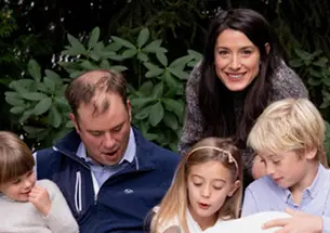 Milano Buckley looks up and smiles in a family photo where her husband and three children are all looking down.