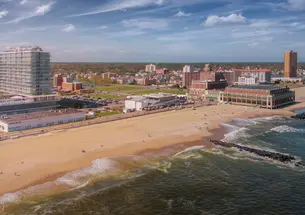 An aerial photo of Asbury Park in New Jersey showing the shore line of the beach and buildings in the background.