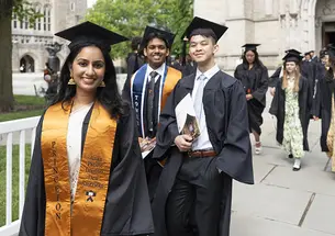 Seniors in their caps and gowns walk out of the University Chapel.