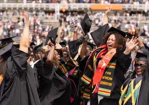Group of students jumping and cheering at Commencement.