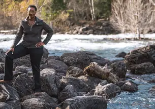 Monica Harris standing on rocks near a swift moving creek in Montana
