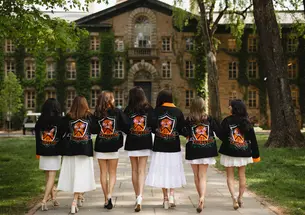 A group of Princeton women from the class of 2025 facing Nassau Hall while wearing their class jackets.