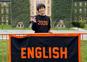 LaurenBlackburn_english_cropped.jpg Lauren Blackburn ’26 stands smiling behind a fence with a banner that reads ENGLISH in orange on a black background.