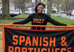Undergrad Alli Ebanks stands behind the Spanish and Portuguese banner at Declaration Day